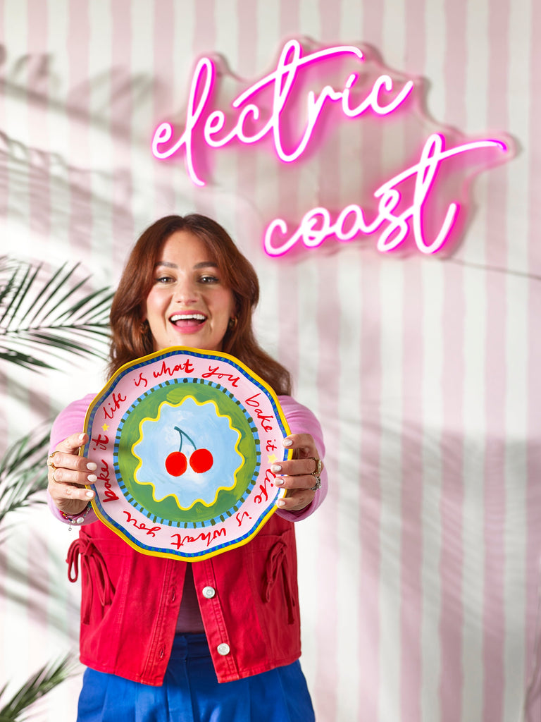 Close-up of Electric Coast Cake Plate glossy stoneware surface with red cherries pattern